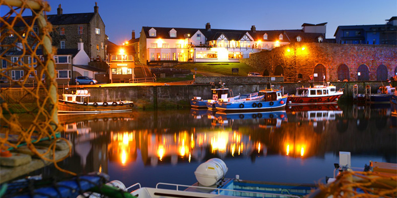 Bamburgh Castle Inn at dusk overlooking Seahouses Harbour in Northumberland