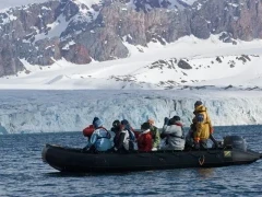 People admiring a glacier from a Zodiac, in Svalbard, Norway.