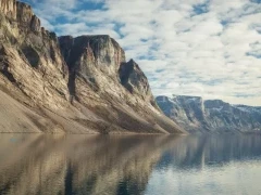 Baffin Island cliffs reflecting in calm waters, Arctic Canada.