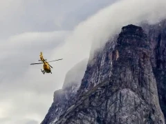Helicopter flying towards island cliffs, Arctic Canada.