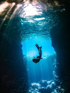 A woman snorkelling down into a cavern in Tonga, South Pacific.
