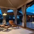 A relaxing lounge area at The River Lodge at twilight, along with the camp's dining tent in the background.