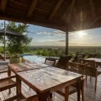 View of the outside area, with dining seating, sun loungers and swimming pool, overlooking Klaserie Private Nature Reserve, South Africa.