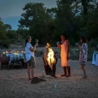 Guests enjoying the outdoor dining experience with fire pit at Simbavati Camp George, South Africa.