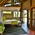 One of the bedroom suites at Rhino Post Safari Lodge, with French doors opening up the room to the private decking area.