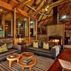 The indoor lounge area at Rhino Post Safari Lodge for guests to relax, featuring a log burner for cooler evenings.