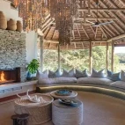 Large relaxing lounge seating area at Dulini River Lodge, complete with wood-burning fire and views of Sabi Sands Game Reserve.