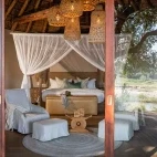 External view of a suite bedroom, complete with ottoman and relaxing chairs at Dulini River Lodge.