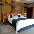 The master bedroom at Amber Villa, Sabi Sabi Earth lodge, featuring a magnificent headboard carved from local matumi wood.