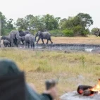 Guest enjoying a coffee by the camp fire at Kweene Trails, Botswana.