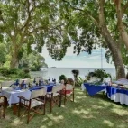Young family members relaxing in the alfresco dining area at Mfangano Island Lodge, Kenya.