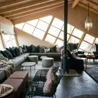 View of the communal lounge, with wraparound seating and wood burner.