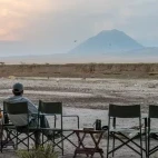Guest enjoying the view of Salei Plains and the Ol Doinyo Lengai Volcano in the distance. At Salei Plains Mobile Tented Camp.