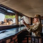 Woman taking an image of elephants from the hide at Sable Valley Lodge.