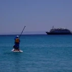 Paddleboarder enjoying the Sea of Cortez, Mexico, with the Safari Voyager in the background.