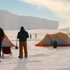 Two guests enjoying the view of the emperor penguins from Gould Bay Emperor Penguin Camp in Antarctica
