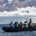 People admiring a glacier from a Zodiac, in Svalbard, Norway.