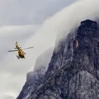 Helicopter flying towards island cliffs, Arctic Canada.